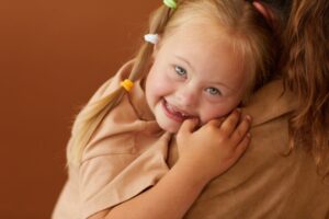 Mother holding autistic daughter on her shoulder.