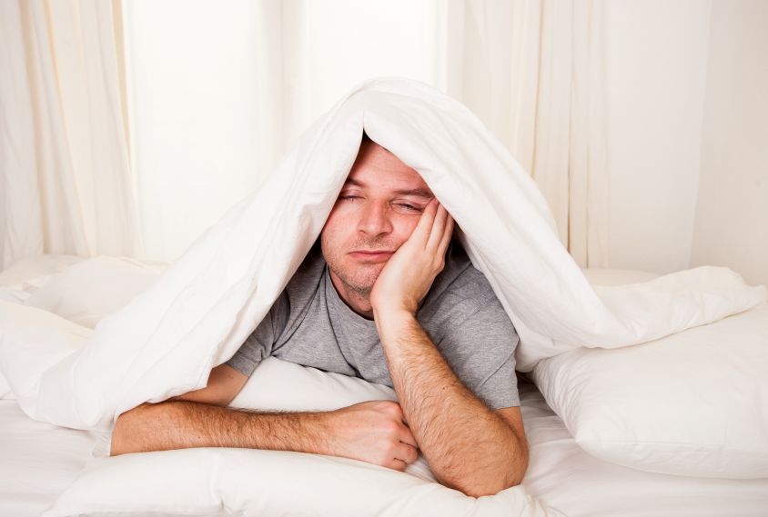A tired man sitting in bed