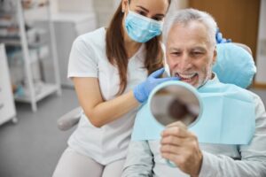 Senior man looking into mirror in dentist's chair. 