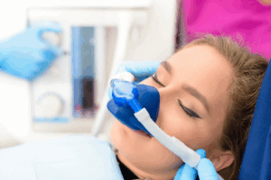 Dentist placing a nitrous oxide mask over patient’s face as they relax