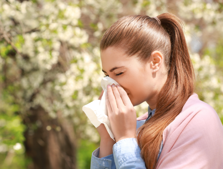 Woman blowing nose outside in a park