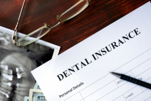 Dental insurance form on a desk next to a dental X-ray and glasses