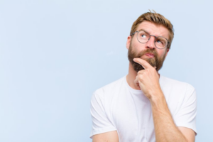 Man rubbing his chin and looking upwards in a questioning pose