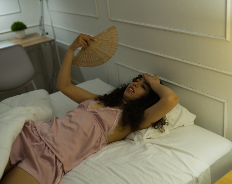 Woman laying in bed with wooden fan